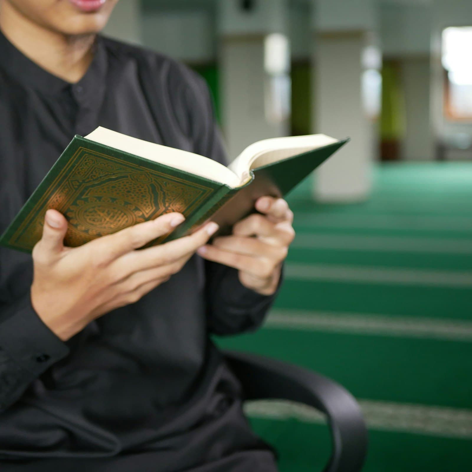 An adult reading the Quran inside a mosque