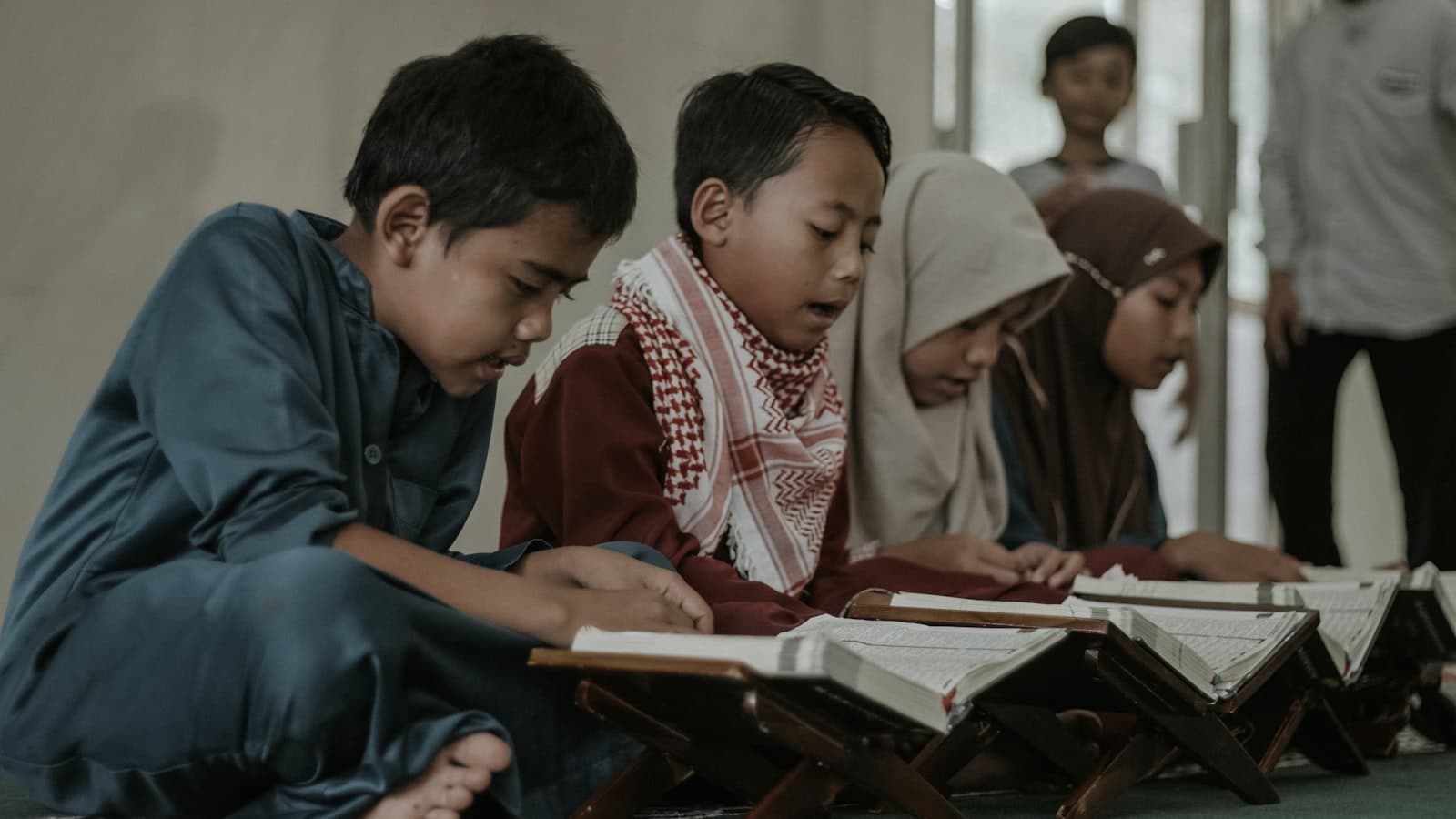Children reciting the Quran together at wooden rehals