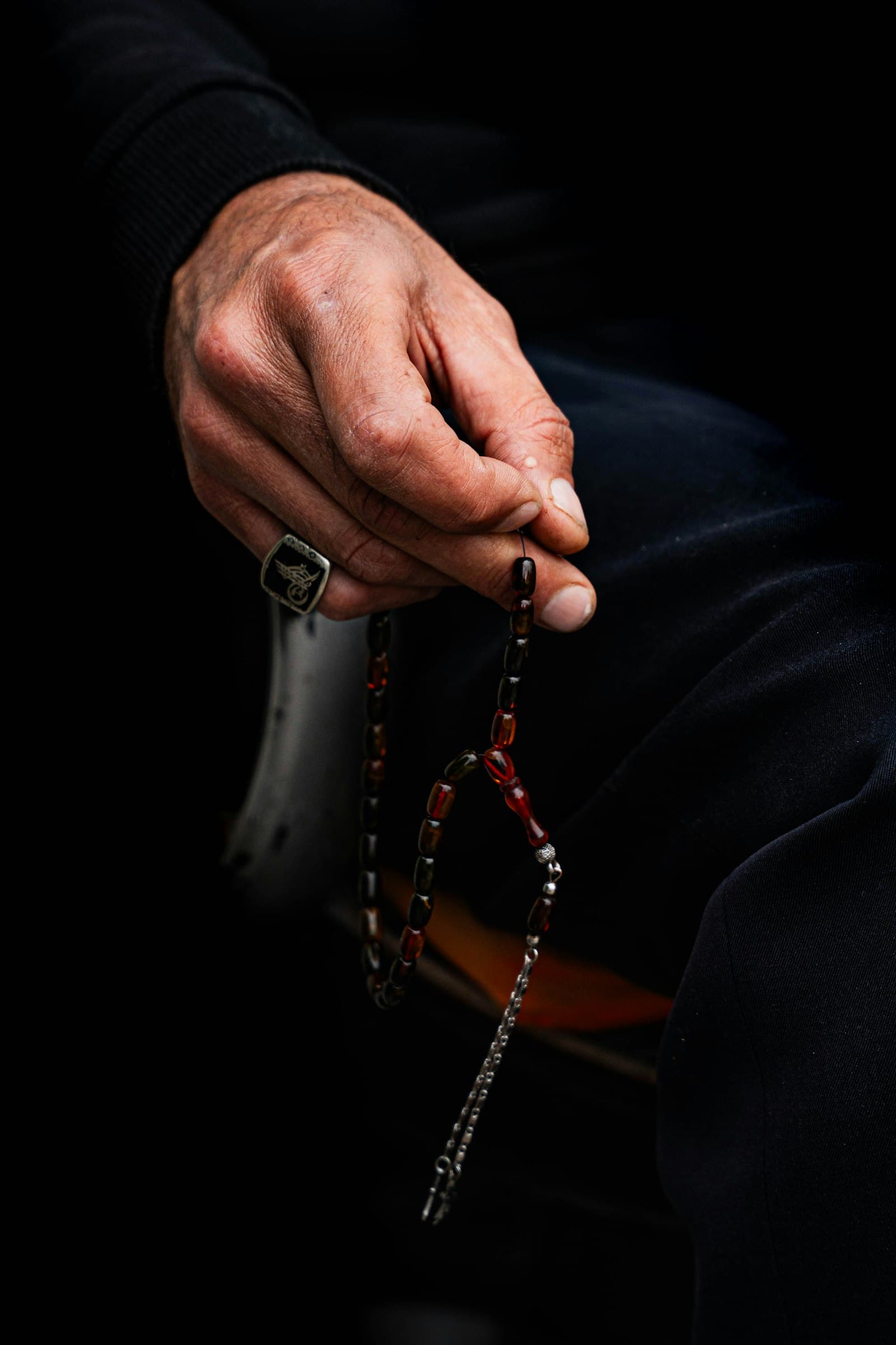 A hand gently holding prayer beads